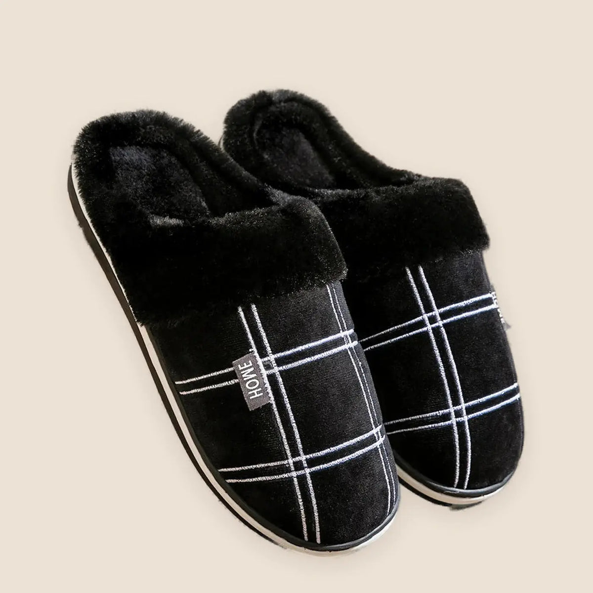 Men's plaid flannel house slippers on a warm neutral background