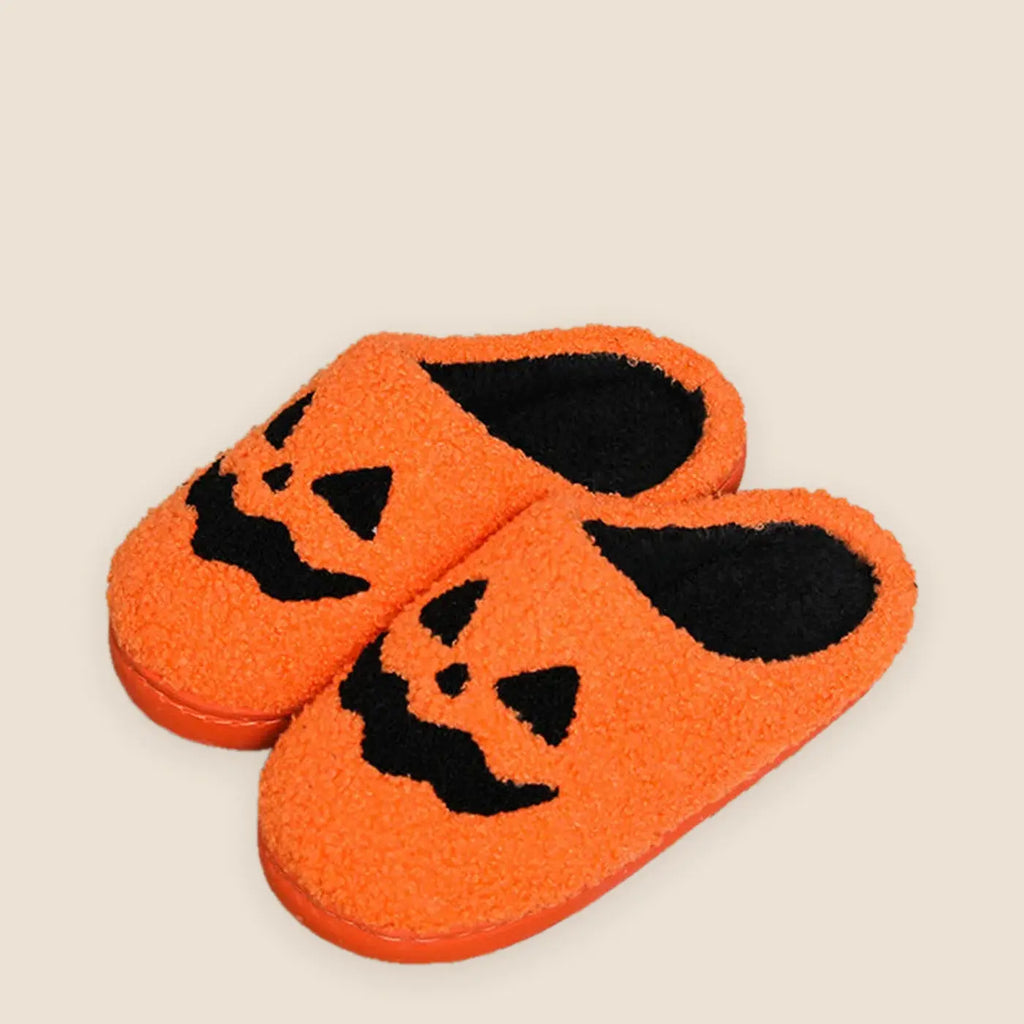 Women's plush pumpkin house slippers on a warm neutral background